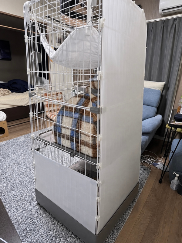 側面と下部に白いパネルを取り付けたトイレ一体型の猫ケージを斜め横から見た様子